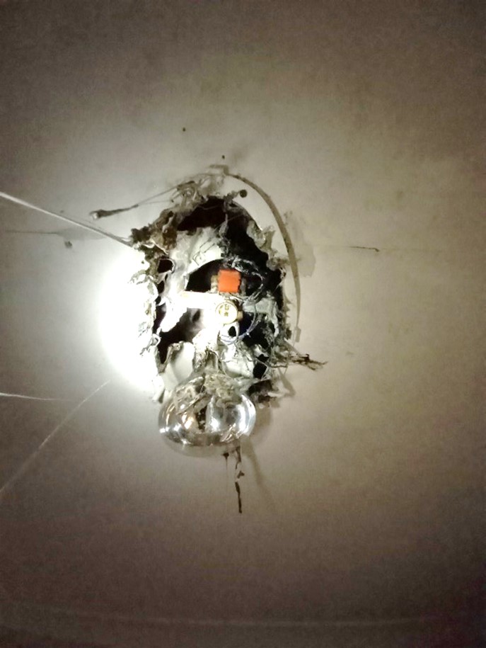 [image] a bathroom fan/light combo in a ceiling with substantial fire damage. 