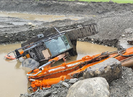 [Image] Orange excavator tipped over in mine pond. 