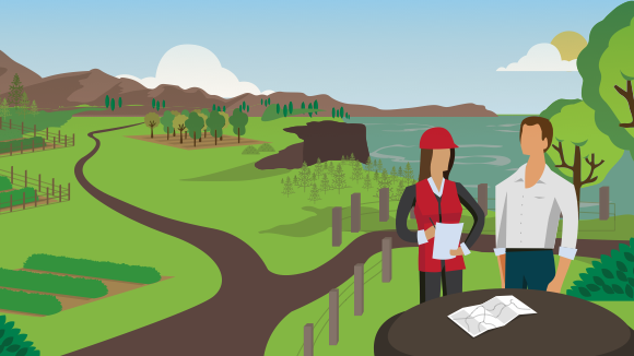 [image] Woman wearing safety gear discussing paperwork with man; a map is spread out on the table with trees, hills and sea in the background