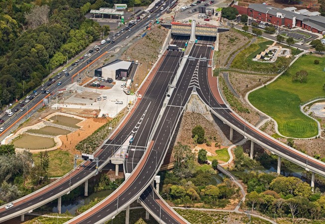 [image] southbound motorway merging into the northern motorway surrounded by green setting.
