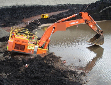[image] Excavator with bucket arm extended tipping forward into a pond