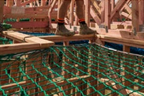 [image] Worker's feet on roof frame next to sagging safety net