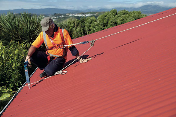 [image] Worker wearing safety harness and making minor roof repairs
